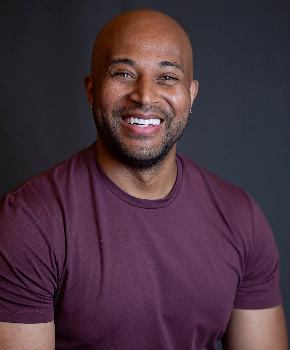 Smiling man wearing a burgundy shirt.