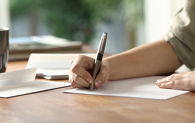 Person writing on paper with a pen.