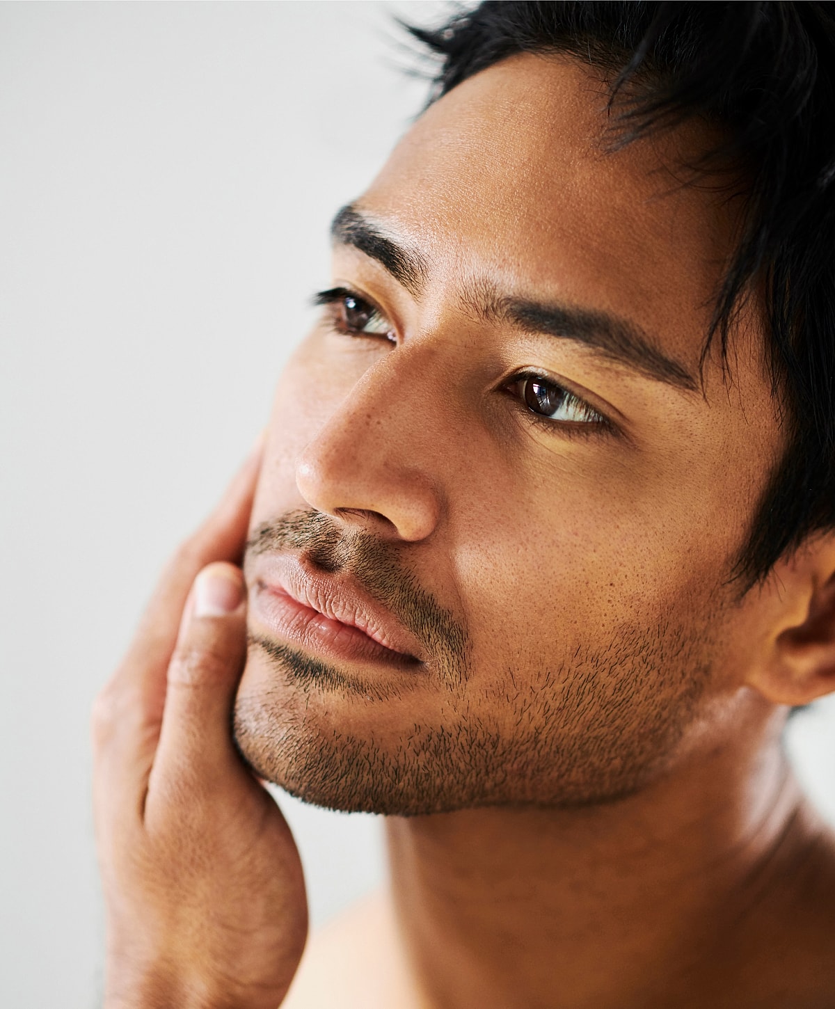 Close-up of a man touching his face.
