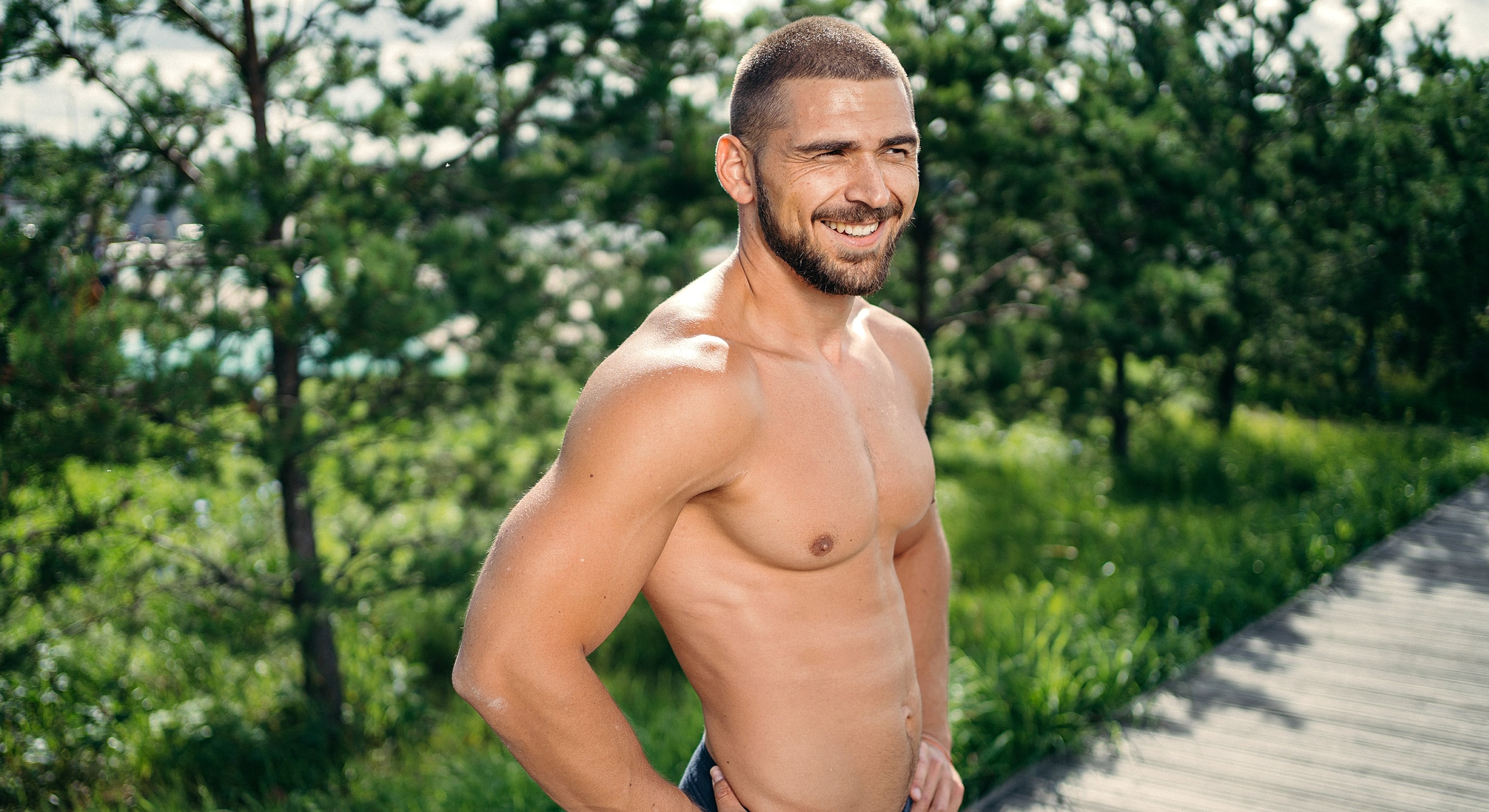 Smiling man in outdoors, showcasing fitness and confidence.