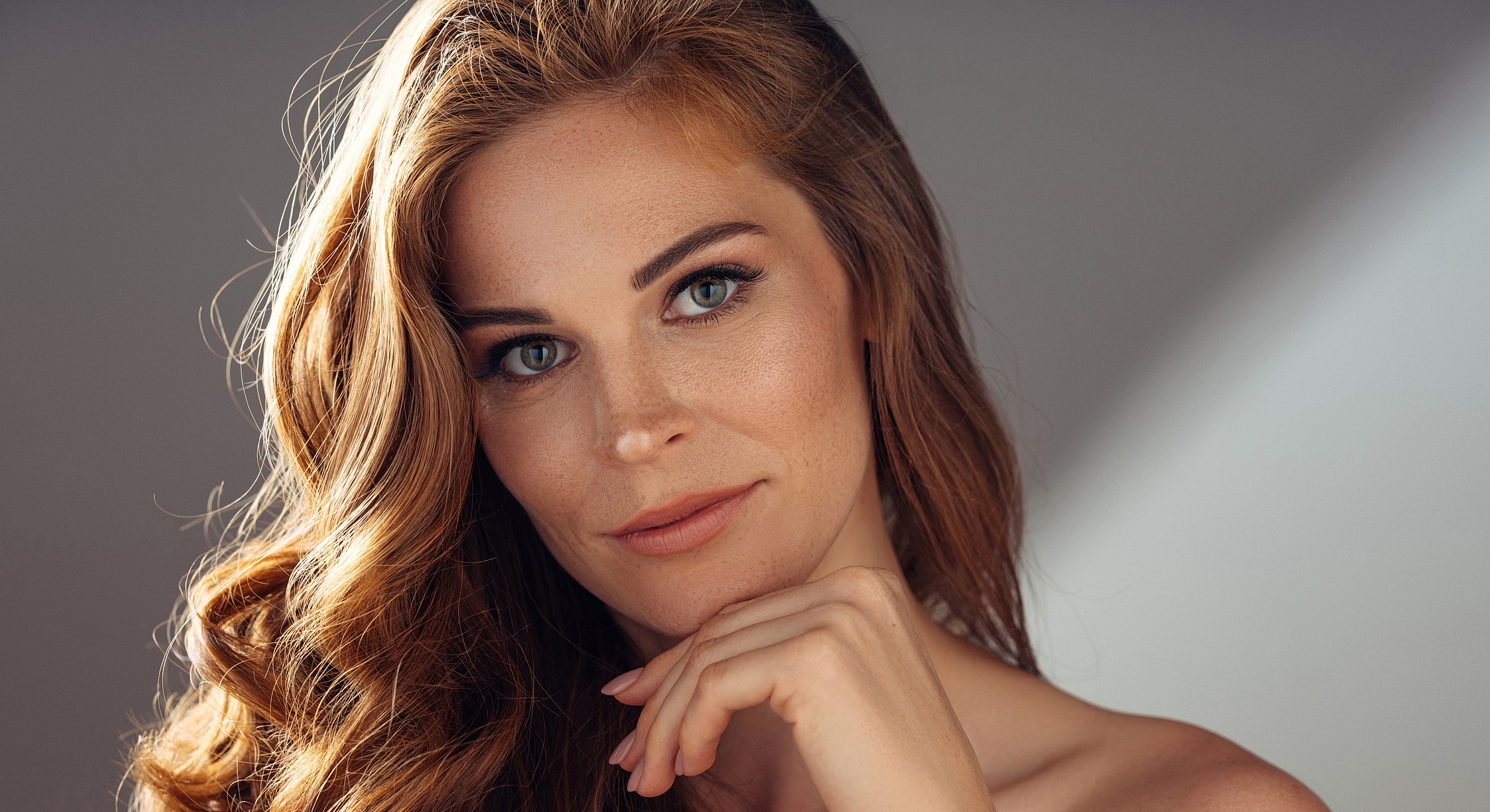 Woman with long wavy hair and thoughtful expression.