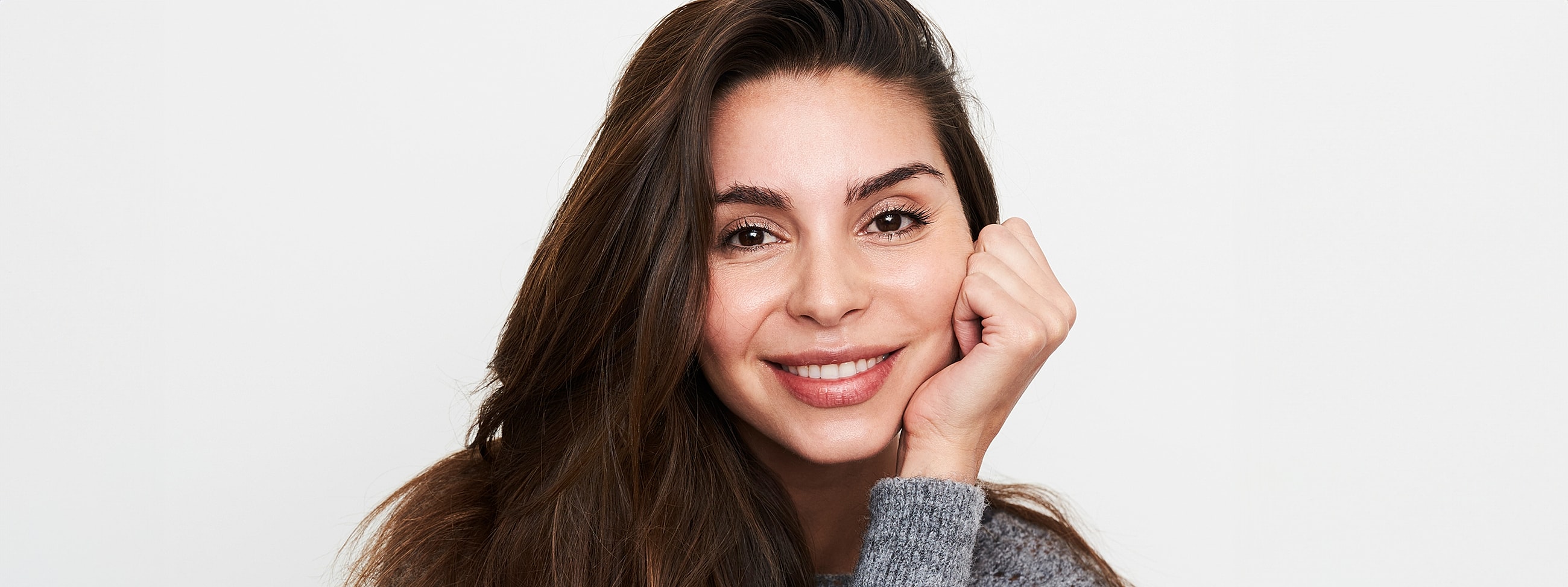 Smiling person with long hair and gray sweater.