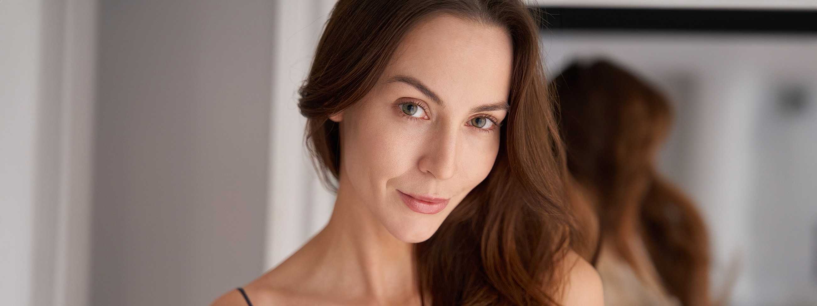 Woman with long hair smiling softly at camera.